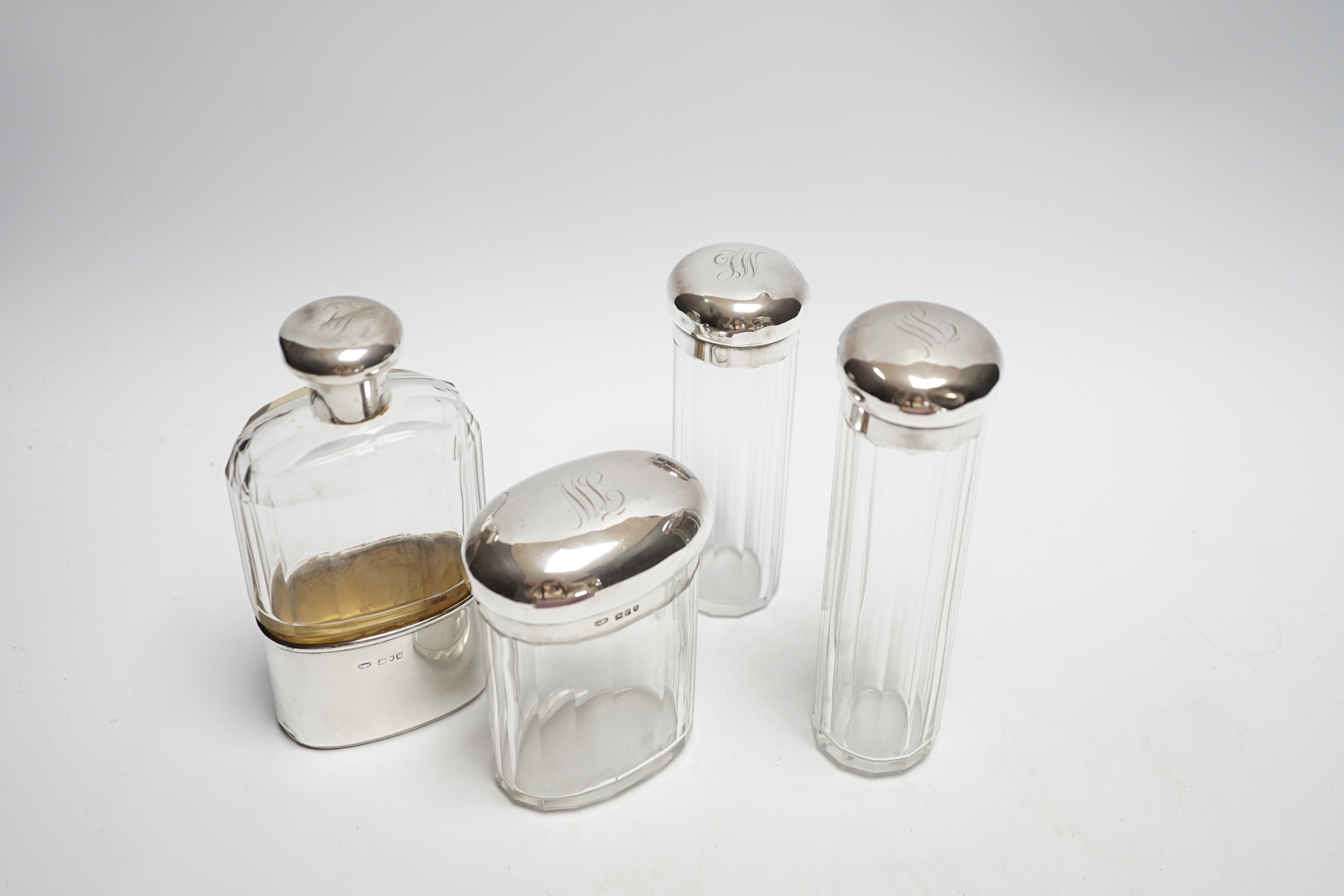 A George V silver mounted glass hip flask, London, 1912, 15.2cm, together with three matching silver mounted glass toilet jars.